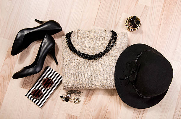 Woman black with silver accessories, high heels, hat, necklace and nail polish.